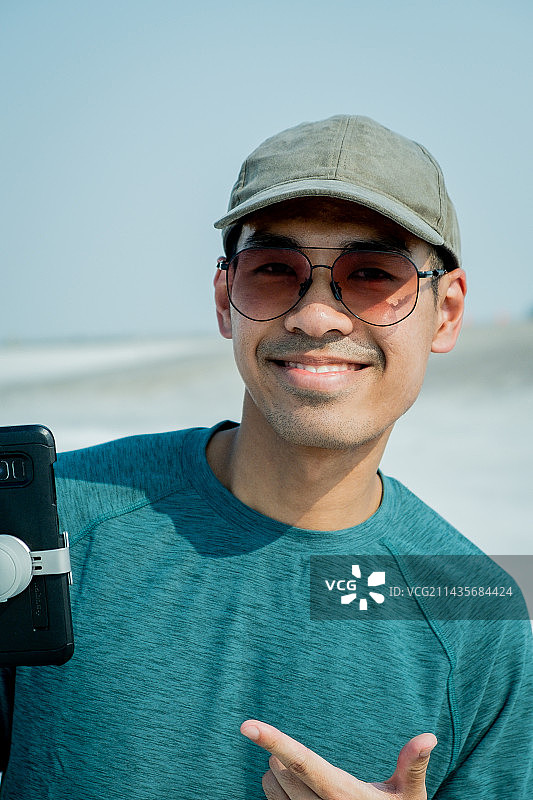 站在白色沙滩上，以晴朗天空为背景的年轻男子肖像，美国犹他州博纳维尔盐滩图片素材