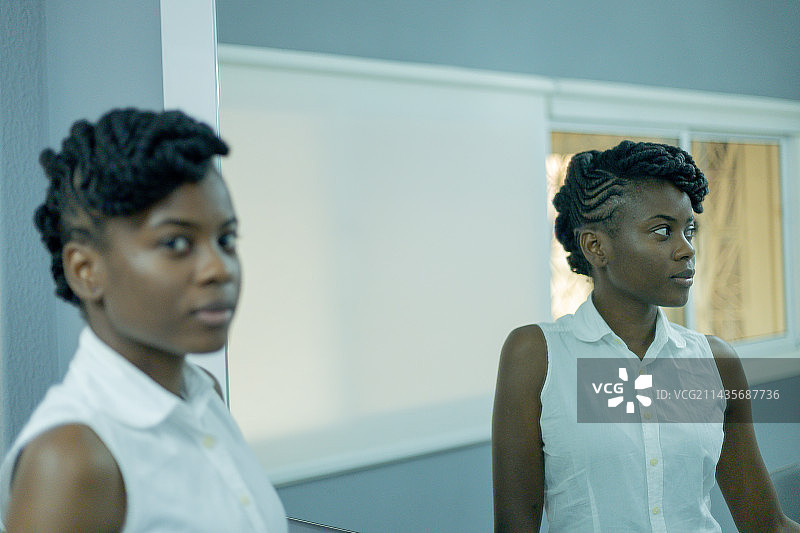 自信的年轻女子站在镜子前，在安哥拉罗安达图片素材