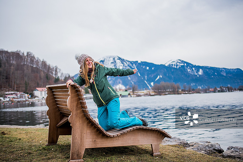 坐在德国泰根湖边木凳上的女人，背景是湖泊和山脉图片素材