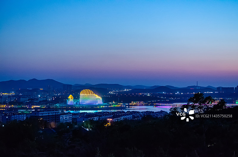 中国山东省泰安市，城市夜晚夜市拍摄主题，泰山西湖标志性建筑和远处的山脉，户外夜晚无人图像摄影图片素材