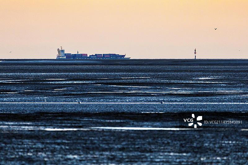 从弗里德里希斯库格-斯皮策看到的景色,一艘货轮在退潮时从易北河口驶向北海,地点:德国石勒苏益格-荷尔斯泰因州弗里德里希斯库格,欧洲图片素材