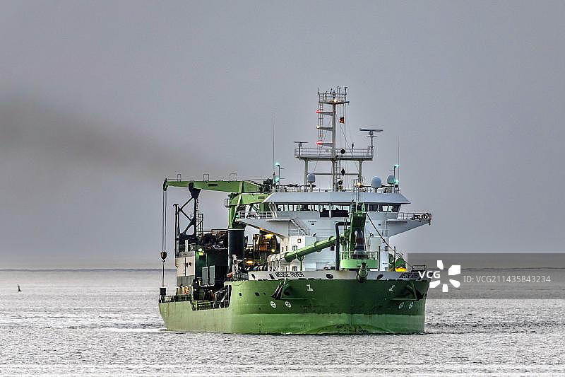 傍晚易北河口的北海，斗轮挖泥船在航道上作业，德国库克斯哈芬，不莱梅，欧洲图片素材