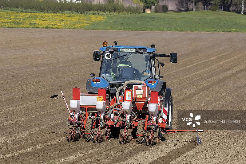 农民用拖拉机在空地上播种玉米图片素材