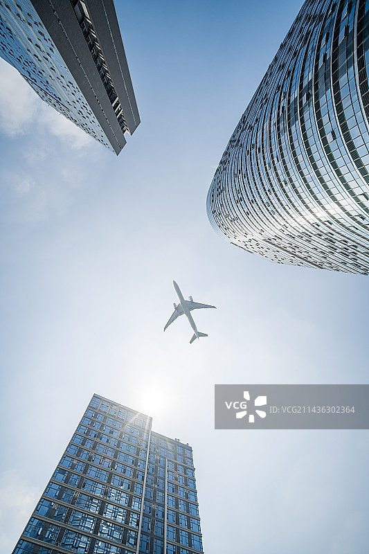 低角度仰拍飞机飞过广州番禺万博写字楼图片素材