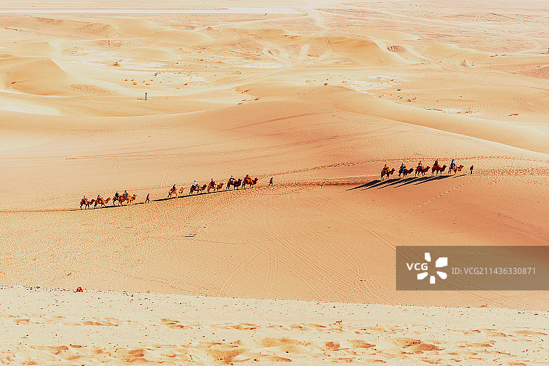鸣沙山中骑骆驼前行的游客图片素材