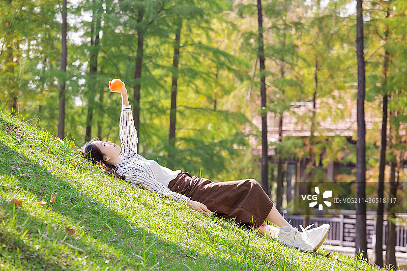 草坪，女性拿着橙子图片素材