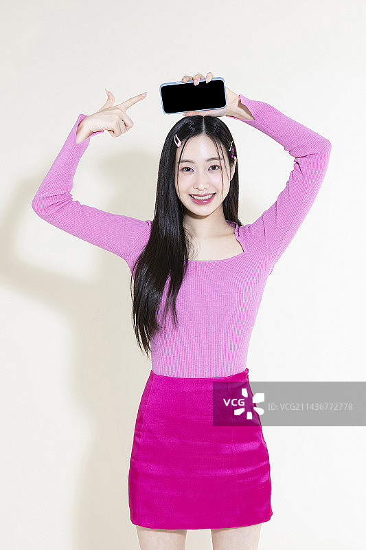 Y2K粉色复古概念照片：手持智能手机的亚洲女性图片素材