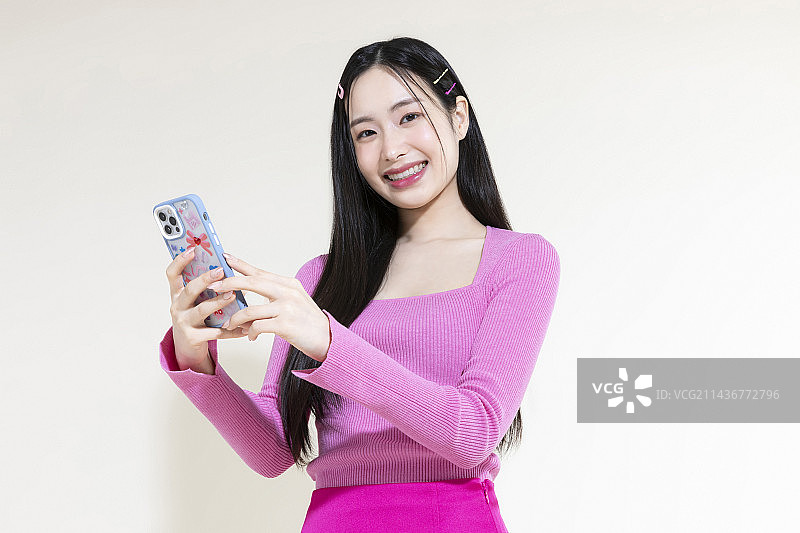 Y2K粉色复古概念照片：手持智能手机的亚洲女性图片素材