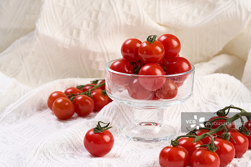 多个串收小番茄放在白布料上的静物图图片素材