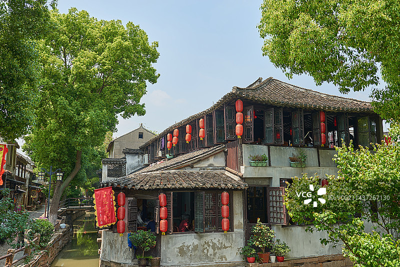 江南水乡古镇的古宅和绿树蓝天以及屋檐下悬挂的红灯笼图片素材