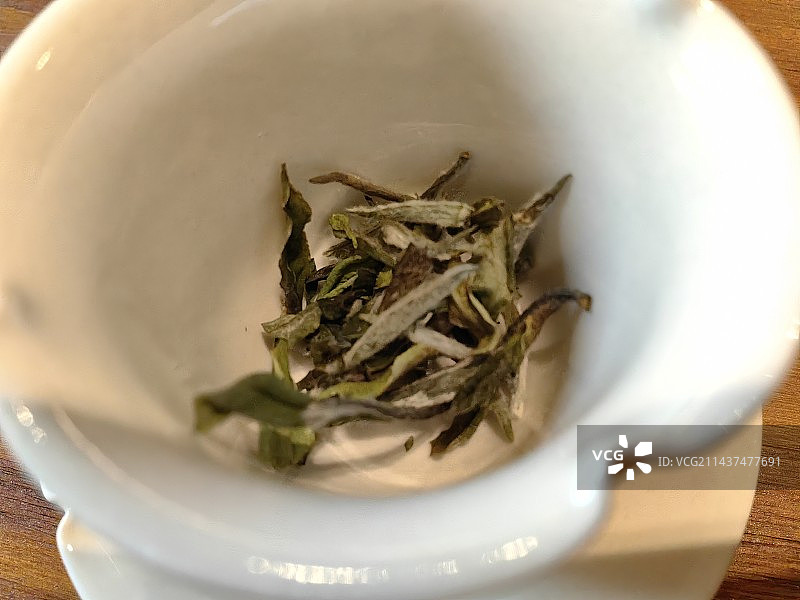 杯中茶，白茶杯里的茶叶，静物特写，木桌上碗里的茶的高角度视图图片素材