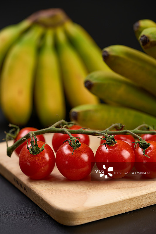 串收小番茄和皇帝香蕉摆放在木板上图片素材