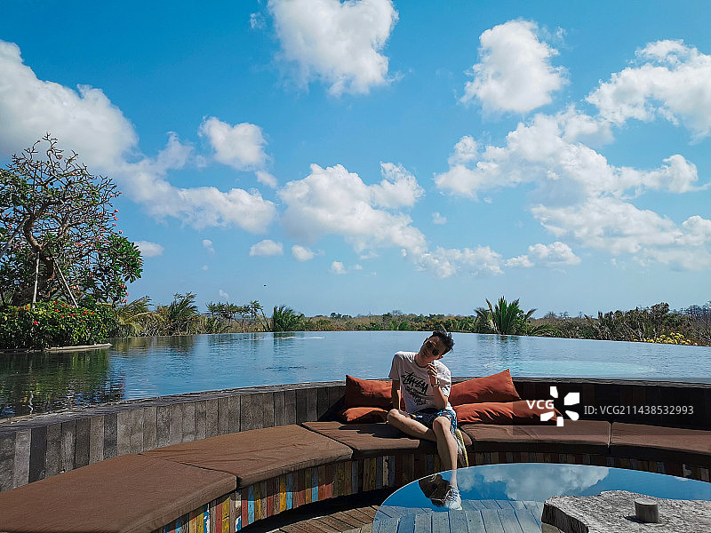 印尼巴厘岛阿雅娜林畔酒店 (RIMBA by AYANA Bali) 坐在室外卡座的男子图片素材