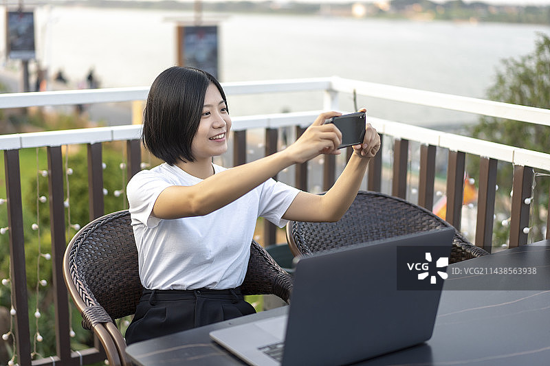 年轻女子在阳台上用笔记本电脑图片素材