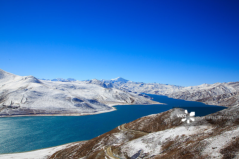 西藏冬季羊湖蓝色湖水与雪山、羊卓雍措、高原湖泊与湖边牧场图片素材