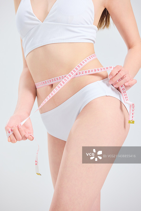 年轻的亚洲女性测量腰围图片素材