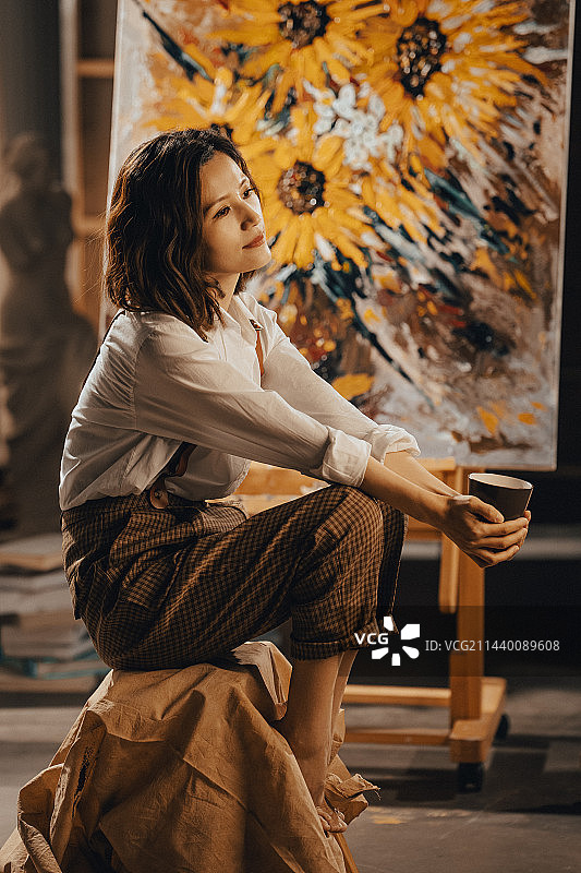 工作室内拿着杯子的青年画家图片素材