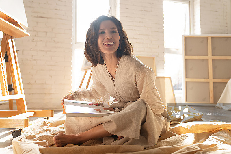 工作室内坐在地上看书的青年画家图片素材