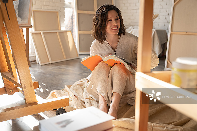 工作室内坐在地上看书的青年画家图片素材