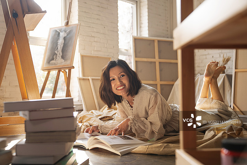 工作室内趴在地上看书的青年画家图片素材