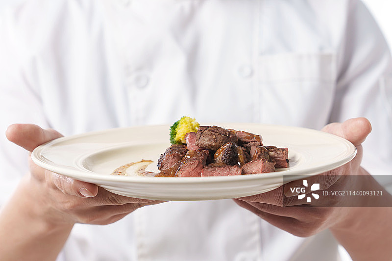 穿着厨师服的中年男人端着美味佳肴图片素材