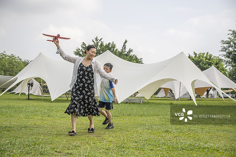夏天公园露营草地上的妈妈和孩子在玩飞机图片素材