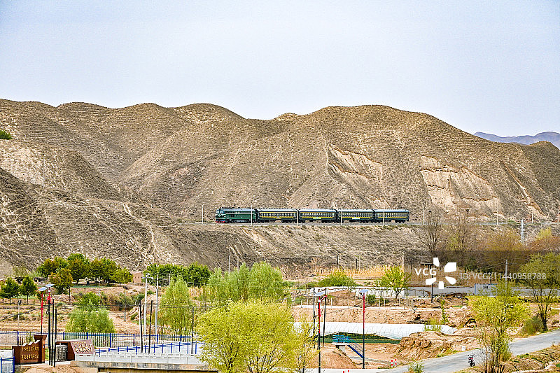 西北群山间，长征惠民号绿皮火车行驶在甘肃白银红会铁路图片素材