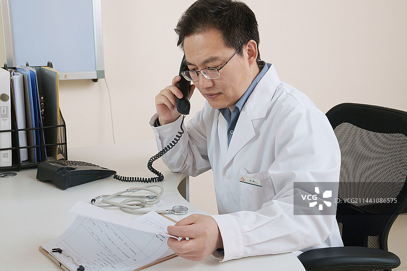 办公室内打电话的中年男医生图片素材
