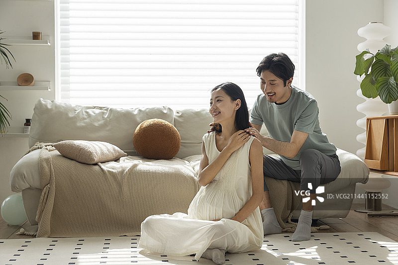 年轻丈夫在客厅给怀孕妻子按摩肩膀图片素材