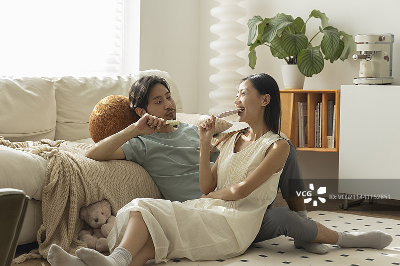 年轻情侣在客厅吃雪糕图片素材