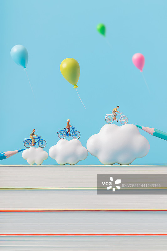 微缩创意书本云朵上骑自行车的少年与气球图片素材