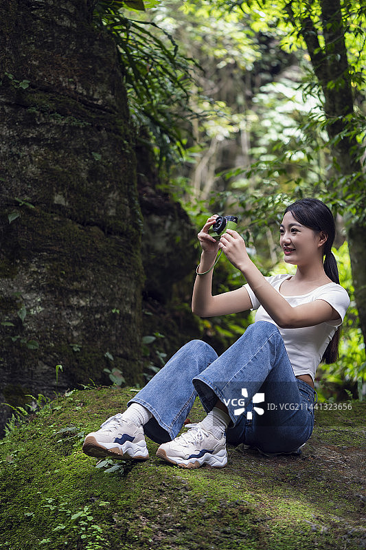 一位美女大学生在湖北恩施梭布垭石林景区的森林里拍照和游玩图片素材