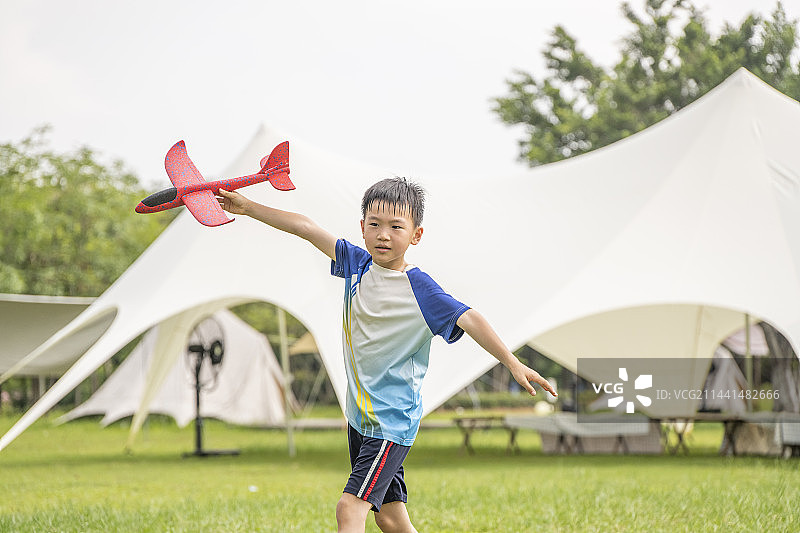 公园露营草地上玩飞机的小男孩图片素材