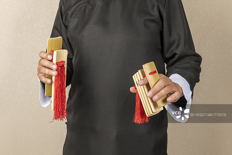 身穿大褂的曲艺演员正在演奏快板书特写图片素材