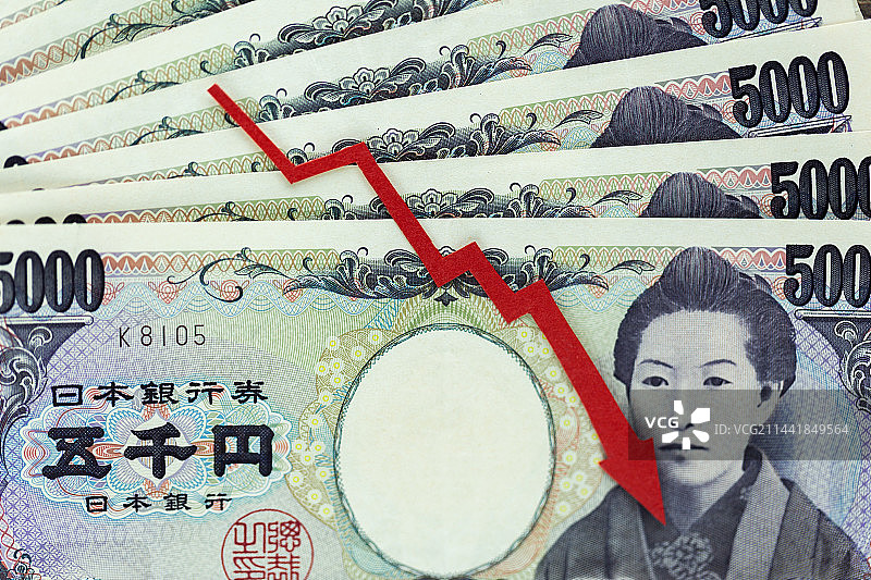 一个红色向下的箭头放在日元纸币上图片素材