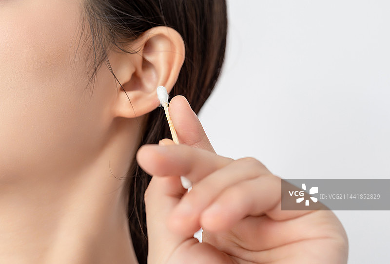 室内一名年轻女性使用棉签清洁耳朵图片素材