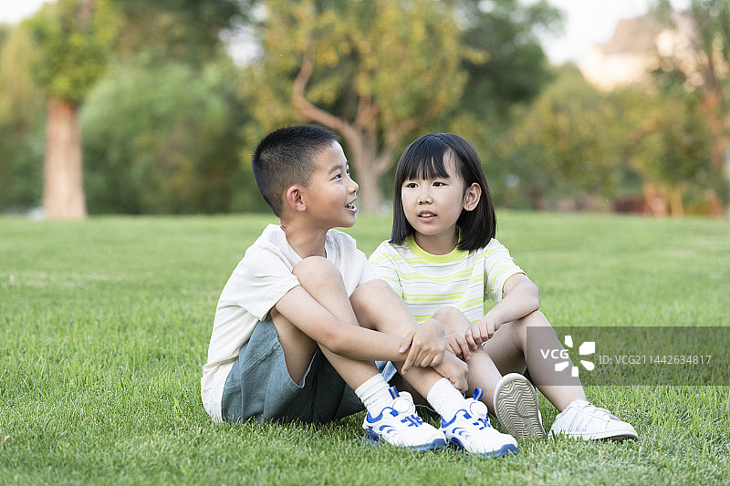 两名小学生坐在草地上交流学习图片素材