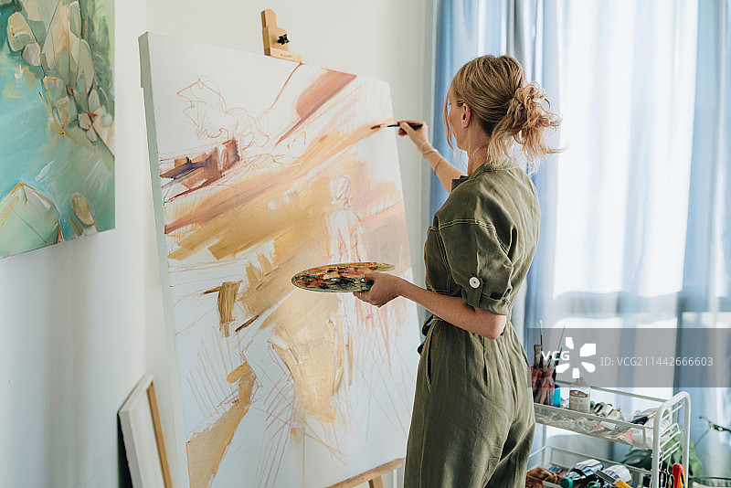 泰国清迈女艺术家在明亮房间内用油画颜料在白色画布上绘画图片素材