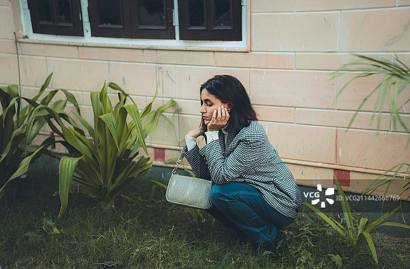 蹲在草地上的时尚年轻女性，印度图片素材