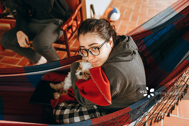 情侣在贝洛奥里藏特米纳斯吉拉斯州家中的吊床上放松身心，旁边有一只小宠物狗图片素材