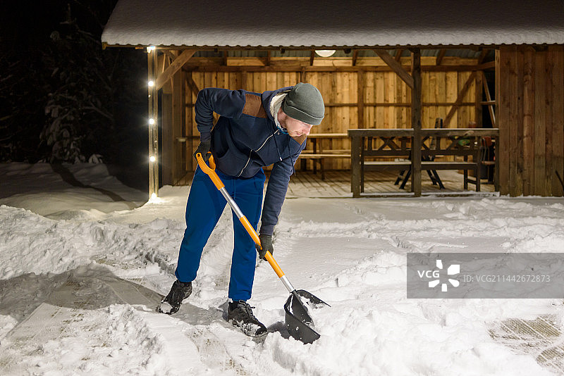 男人在爱沙尼亚里斯蒂清理院子里的积雪图片素材