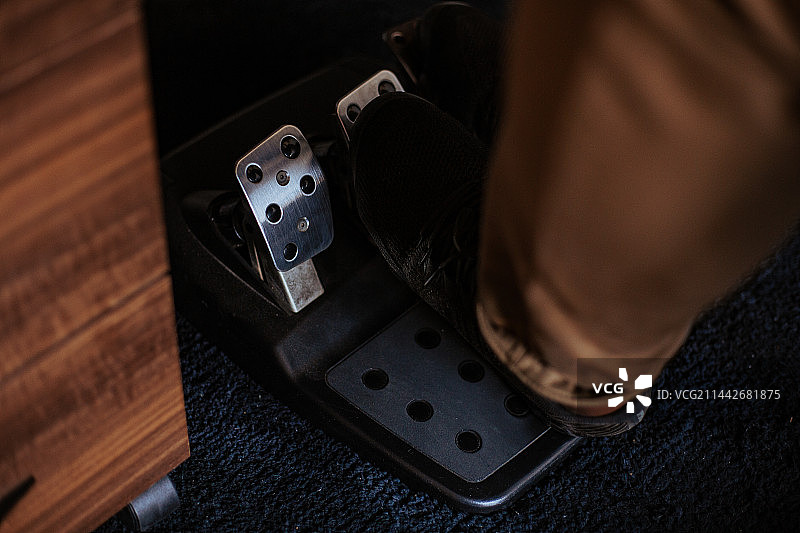 男子在加纳阿克拉的家中坐在椅子上使用脚踏游戏机的背影图片素材