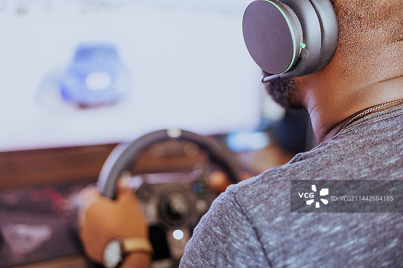 男子戴着耳机坐在家里的椅子上玩游戏机，阿克拉，加纳图片素材