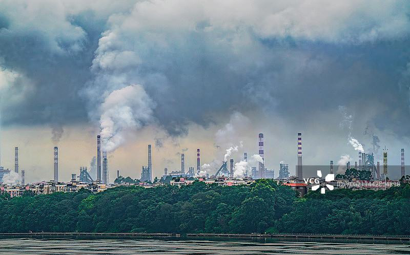 烟囱林立的工厂，从烟囱里冒出的烟在工厂上空形成了一片云层图片素材