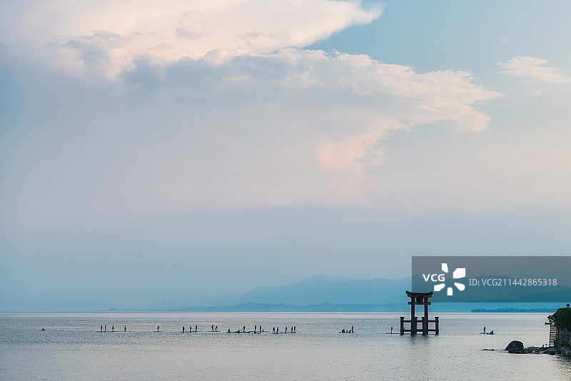 日本京都滋贺县高岛市琵琶湖边（白须神社）水上鸟居与一群划桨板的人夏季户外剪影图片素材