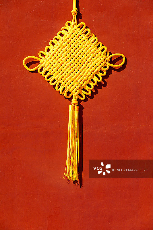 红墙上悬挂着黄色的中国结图片素材