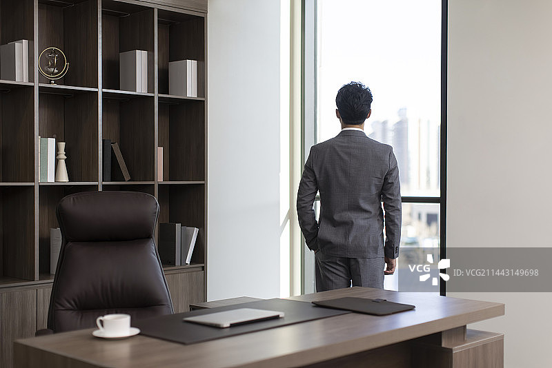 Successful businessman looking through window图片素材