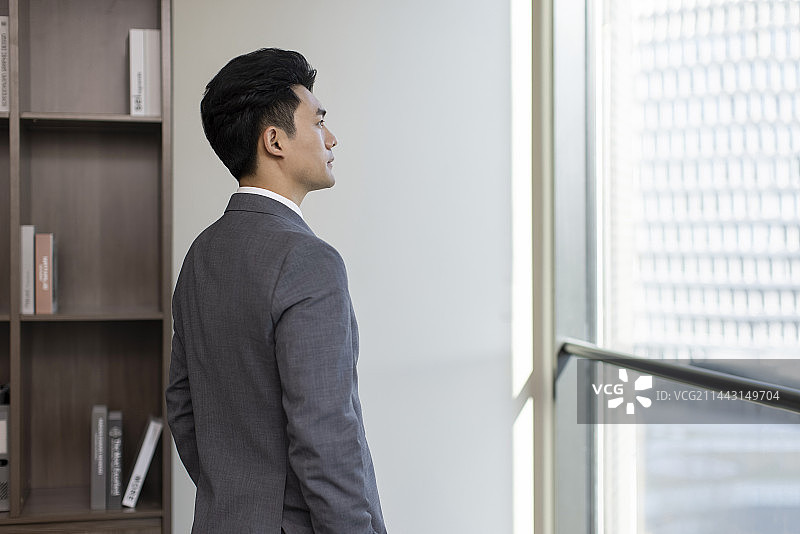 Successful businessman looking through window图片素材