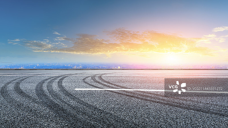 日落高视角沥青路面和城市天际线图片素材
