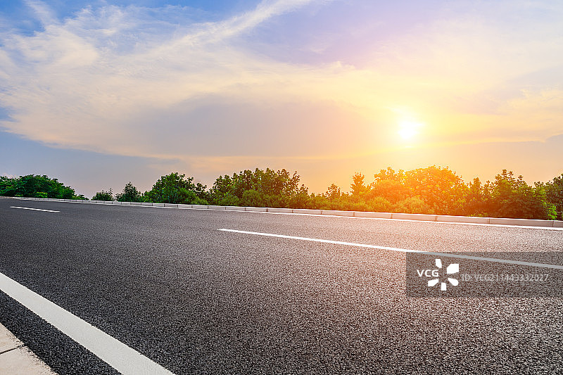 空的沥青路面和树林与云景在日落时图片素材